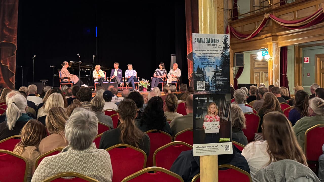 Många människor som lyssnar på ett antal personer som för ett panelsamtal på en scen.